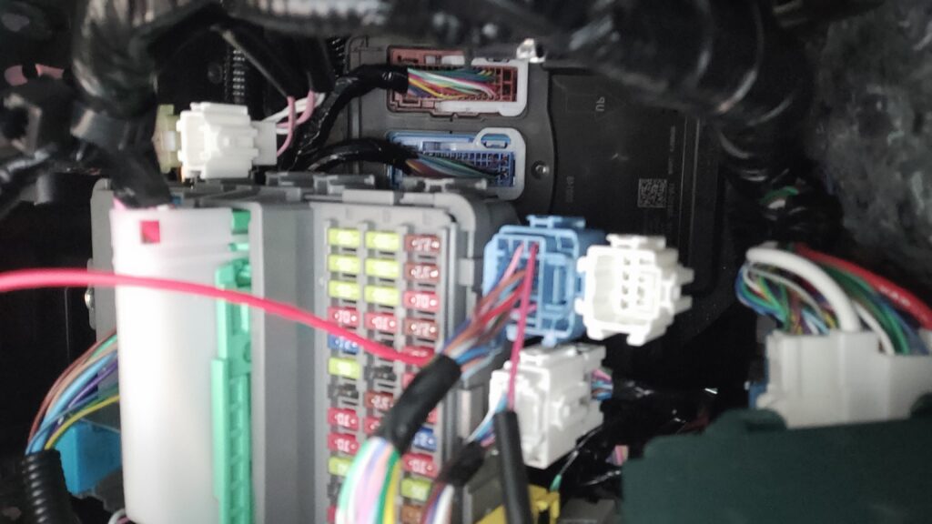 新型フリードのヒューズボックス周辺で車速連動ドアロックキットの配線カプラーを割り込ませている施工中の様子